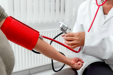 Blutdruckmessen bei Patientin in Arztpraxis, Blutdruckmessgerät und Stethoskop
