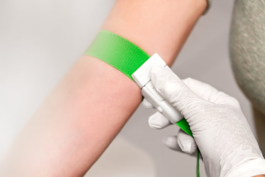 Staubinde oder Venenstauer wird um den Arm gebunden, Patient und Arzt