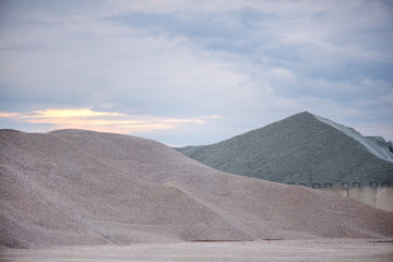 Fototapeta na wymiar Large piles of construction sand and gravel used for asphalt production and building. Limestone quarry, mining rocks and stones 