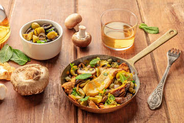 A rustic mushrooms and olives saute with mint and a glass of white wine