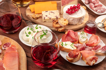 Wine tasting and pairing. A wineglass with sandwiches and a cheese platter on a dark wooden background