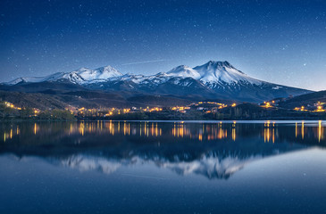 natural background with snow-covered volcano, starry sky with Milky way and reflection in a mountain lake - obrazy, fototapety, plakaty