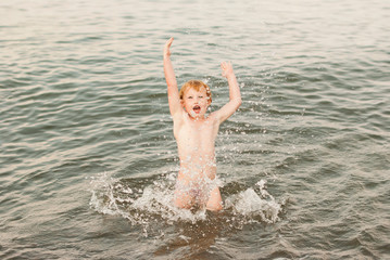 child is having fun in the water, in the sea, sea spray, happy childhood, summer joys, family holidays