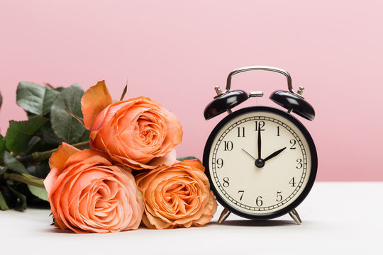 rose roses and clock on pink background, daylight saving.