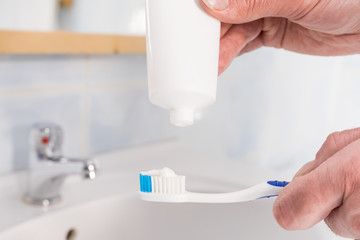 Person putting toothpaste on toothbrush