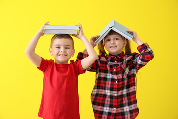 Cute little children with books on color background