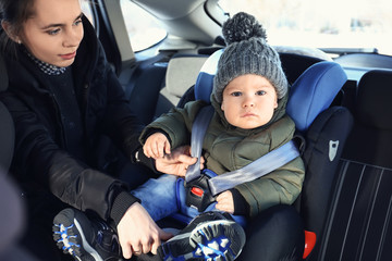 Mother buckling her baby in car seat