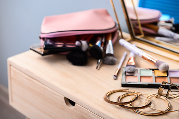 Golden jewelry with makeup cosmetics on dressing table