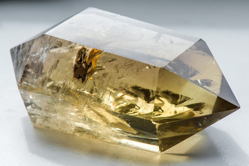 Macro shot of citrine stone on white background. Yellow, clear crystal with a dark, smokey color,...
