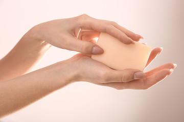 Female hands with soap bar on light background