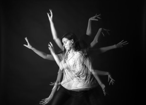 Stroboscopic photo of young woman with moving arms on dark background