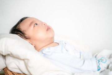 Infant baby lying on blanket in wood baket on white background