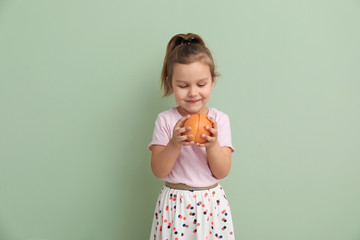 Portrait of cute little girl with halves of grapefruit on color background