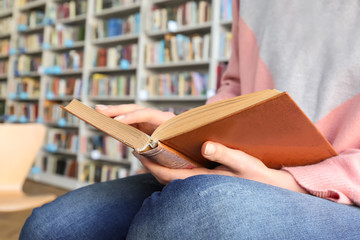 Young woman reading book in library, closeup