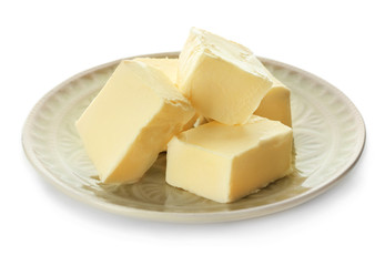 Plate with pieces of butter on white background