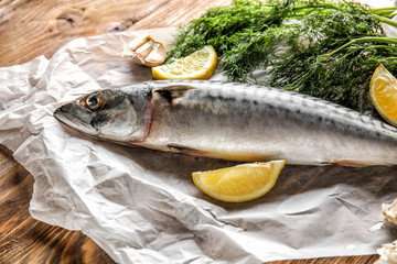 Parchment with tasty raw mackerel fish on wooden table