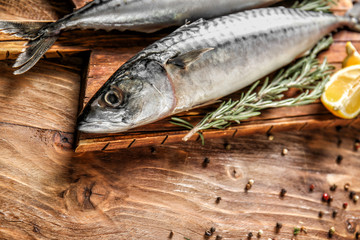 Board with tasty raw mackerel fish and spices on wooden table