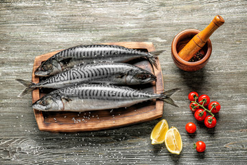 Board with tasty raw mackerel fish on wooden table - obrazy, fototapety, plakaty