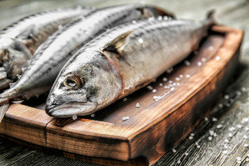 Wooden board with tasty raw mackerel fish on table