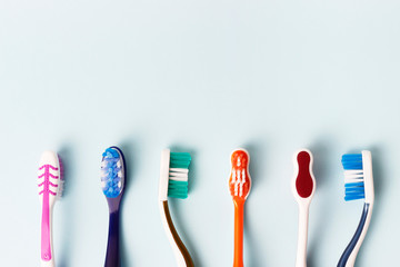 Multi-colored toothbrushes on a blue background, copy space