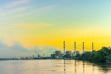 Natural gas electric power plant with smokestack at riverside in chonburi thailand and beautiful golden sunrise sky in morning
