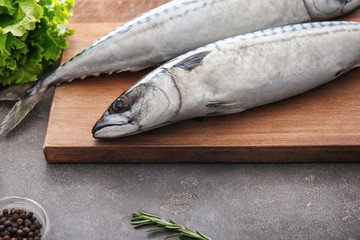 Wooden board with tasty raw mackerel fish on grey table