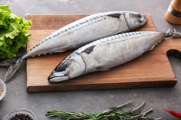 Wooden board with tasty raw mackerel fish on grey table
