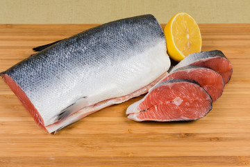 Uncooked salmon steaks against of fish piece and lemon