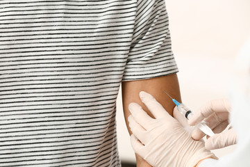Doctor vaccinating male patient in clinic, closeup