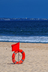 red flag with a lifebuoy on the beach