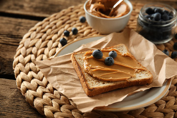 Toasted bread with tasty peanut butter and berries on table