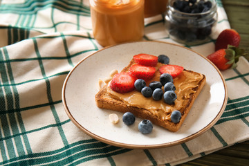 Toasted bread with tasty peanut butter and berries on plate