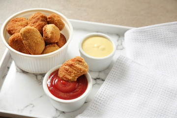 Plate with tasty nuggets and sauces on grey table