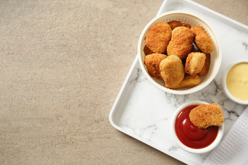 Plate with tasty nuggets and sauces on grey table