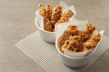 Tasty nuggets in bowls on grey table