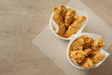 Tasty nuggets in bowls on grey table