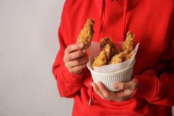 Young woman with tasty nuggets in bowl, closeup