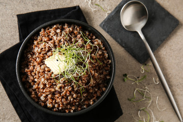 Bowl with tasty boiled buckwheat on grey table