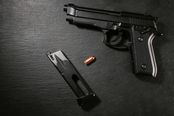 Gun with bullet and magazine on grey background