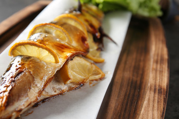 Grilled mackerel fish with lemon on wooden board, closeup
