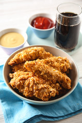 Bowl with tasty nuggets on white table