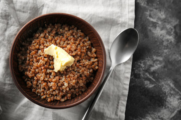 Bowl with tasty boiled buckwheat on table