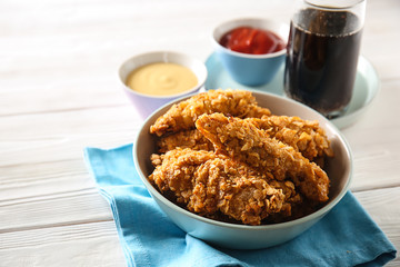 Bowl with tasty nuggets on white table