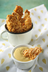 Mug with tasty nuggets and cheese sauce on table