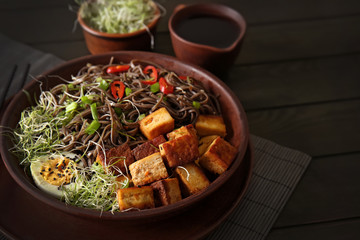 Plate with tasty fried tofu cheese and soba noodles on table