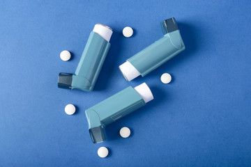Inhalers and pills on color background