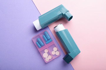 Inhalers and pills on color background