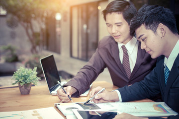 Image of two young asia businessmen using touchpad at meeting