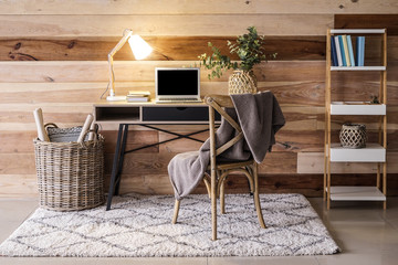 Interior of modern room with comfortable workplace near wooden wall