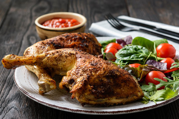 Grilled chicken leg quorters with salad mix and tomatoes.